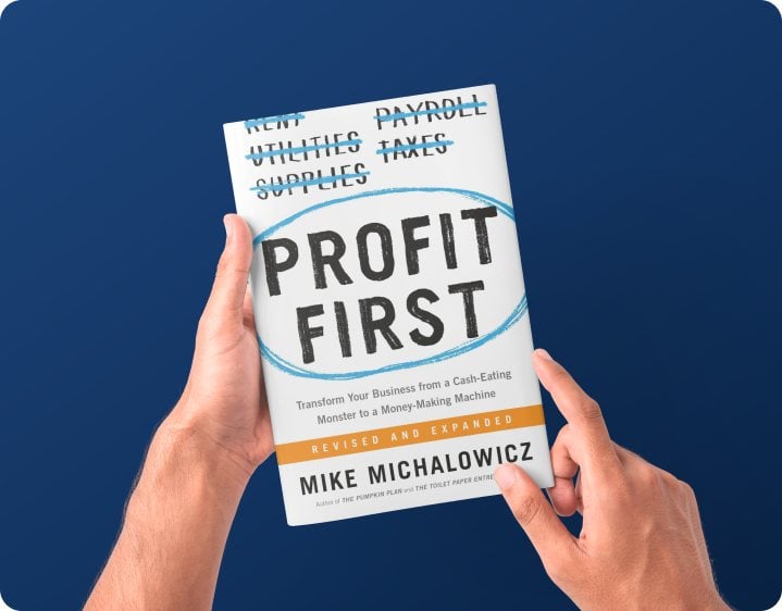 Two hands holding a copy of Profit First by Mike Michalowicz