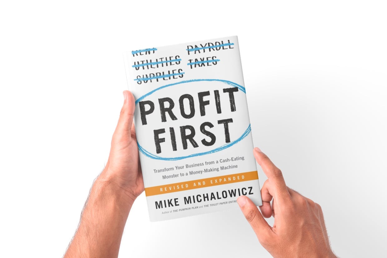 A reader holding an open copy of Profit First