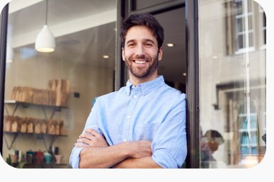 A small business owner standing confidently in the doorway of his shop.